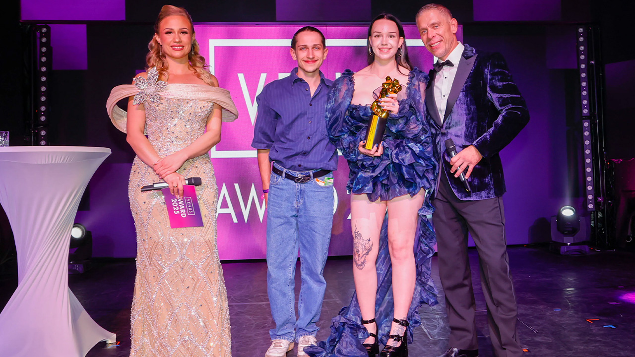 Cassandra Clasen mit Venus Award 2025 Trophäe auf der Bühne zwischen Moderatorin Gabi Gold und Moderator Mick Blue im Wintergarten Varieté Berlin