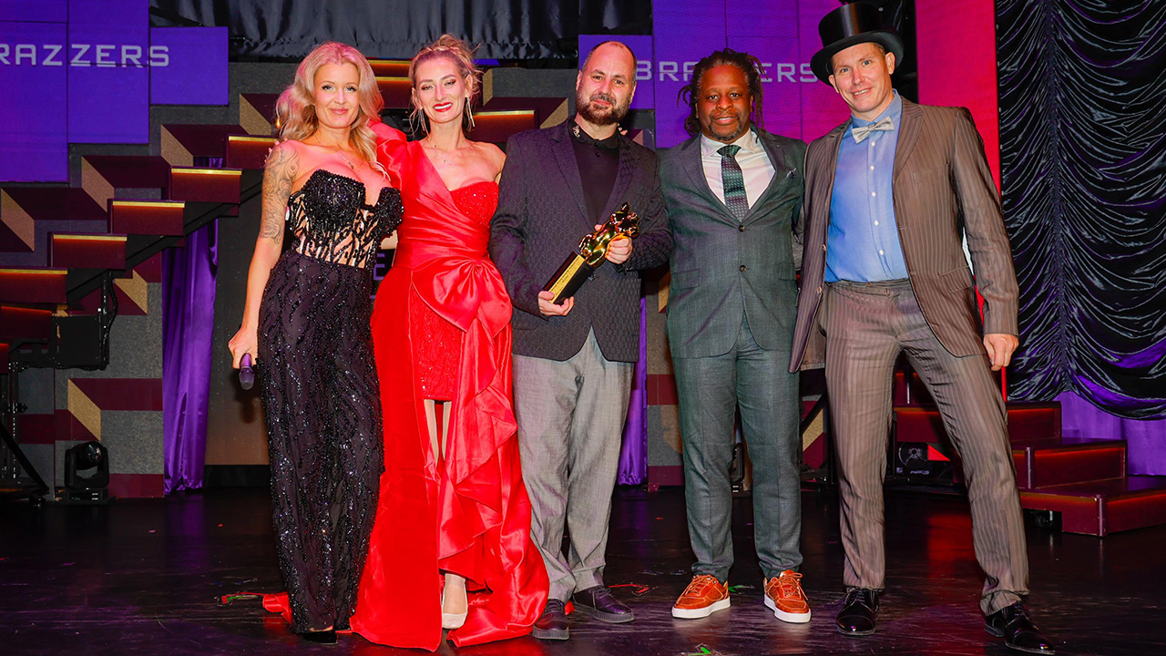 Vika Viktoria und Chris von Vikamodels mit Venus Award 2024 Trophäe auf der Bühne zwischen Moderatoren RoxxyX und Mola Adebisi sowie Ronny Rosetti im Wintergarten Varieté Berlin