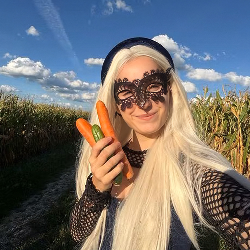 Einfach Anja mit blonder Perücke und Spitzenmaske auf einem Feld